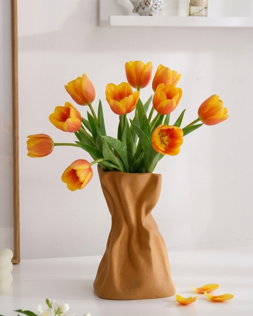 Vase with orange tulips on a white surface with a minimal background