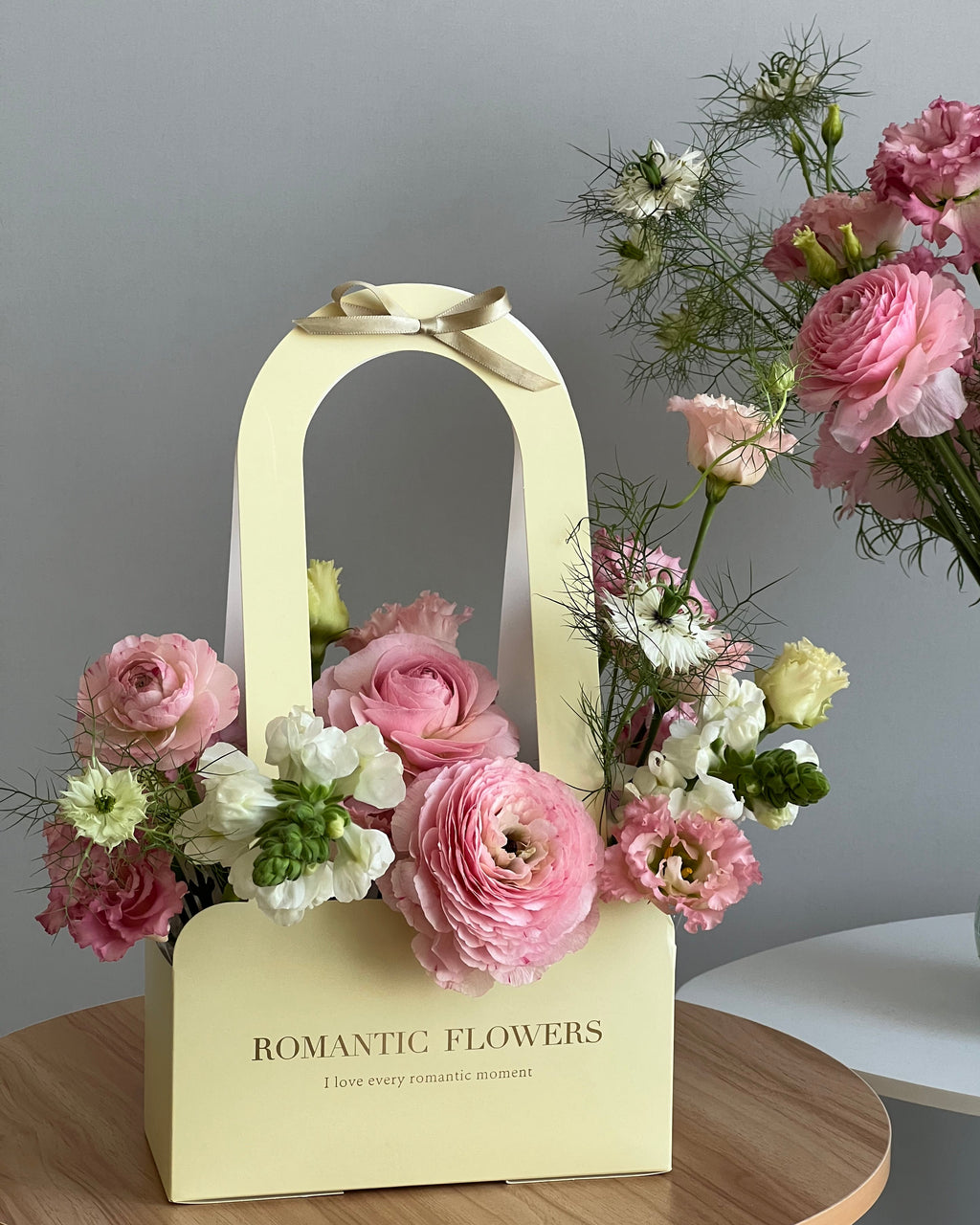 Floral arrangement with a 'Romantic Flowers' box on a neutral background