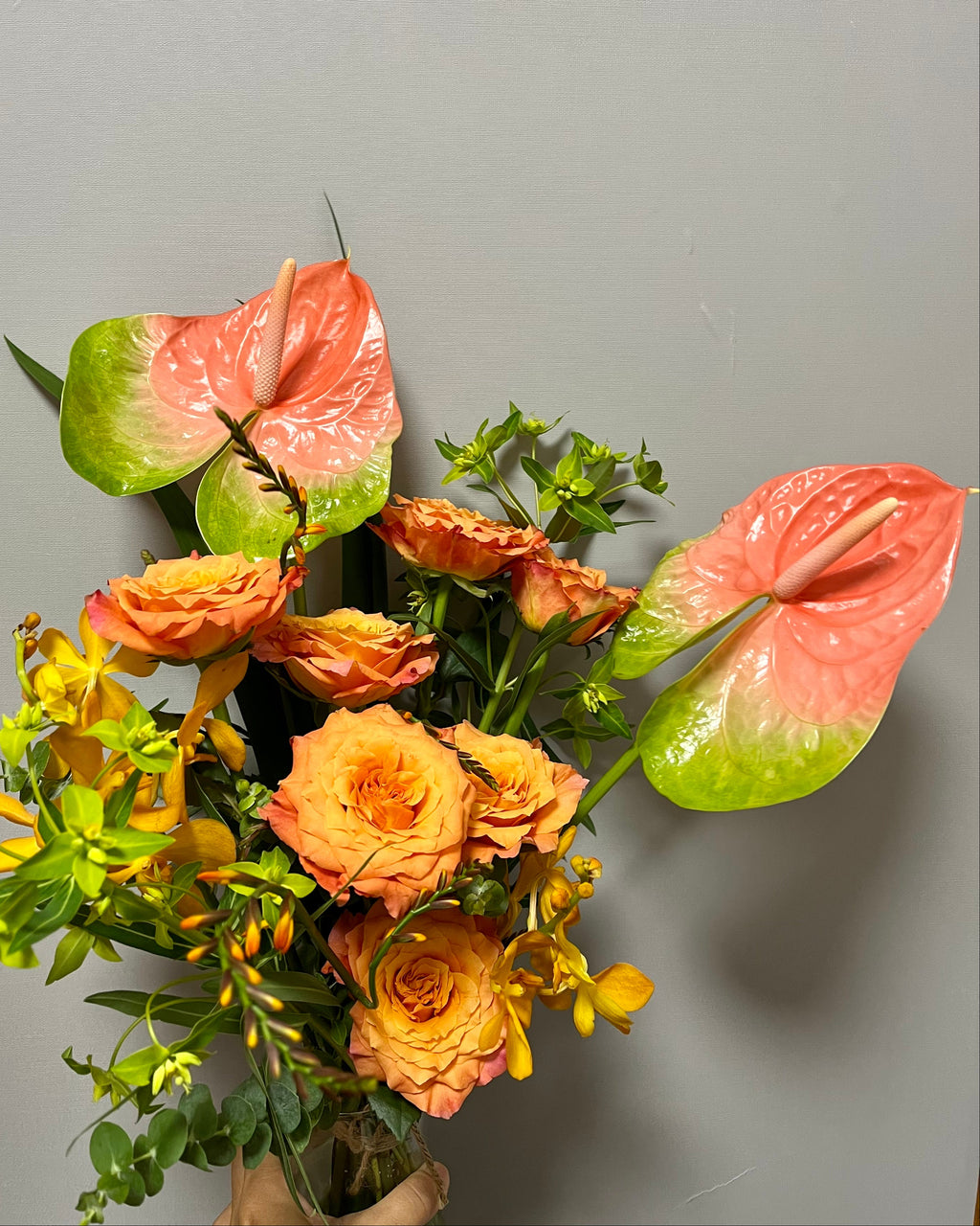 Bouquet of flowers with pink and orange hues against a gray background